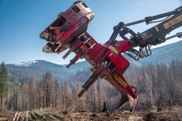 Quadco 22SC upside down connected to a log loader